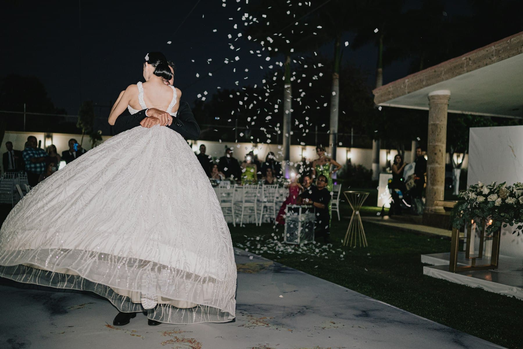 Bride and groom dancing under falling petals at night